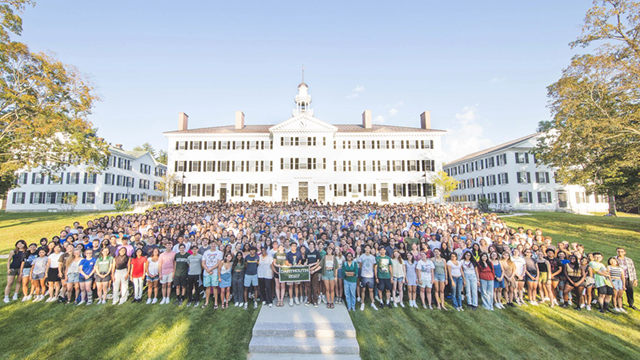 Photo of the entire Class of 2027 standing on the Green with Dartmouth Hall behind them