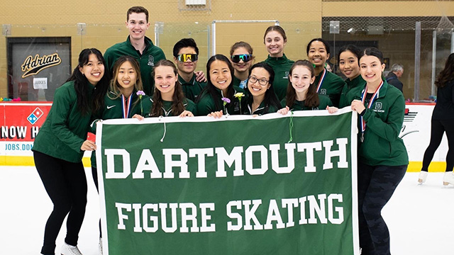 The Dartmouth figure skating team poses on the ice with their Dartmouth banner