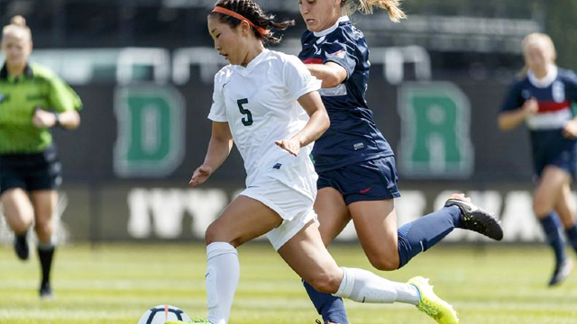 A Dartmouth soccer player races past an opponent toward the goal
