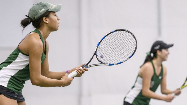 Women's tennis doubles teammates stand ready to return a serve