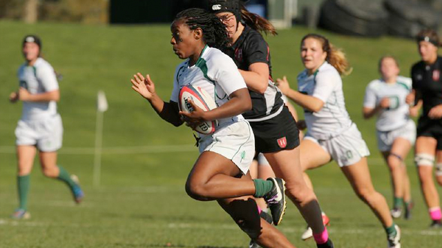 A women's rugby player breaks past an opponent as other chase after her
