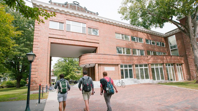 Three students walk on campus toward the Rockerfeller Center