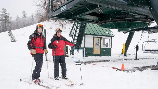 Two Dartmouth ski patrol members stand by the chair lift 