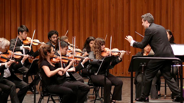 A conductor stands in front of the Dartmouth Symphony Orchestra during a piece performed at Dartmouth