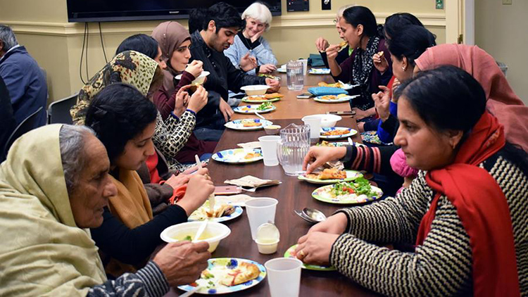A long table full of people sharing a meal at a Friends of Al-Nur event