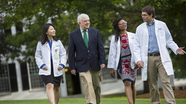 A professor and medical students walk across campus