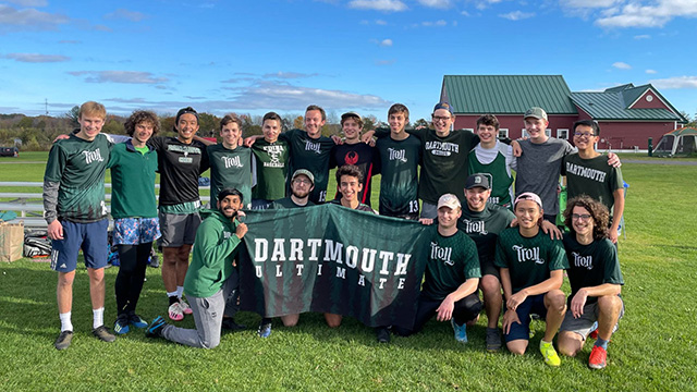 The ultimate frisbee team poses with their Dartmouth banner outside on a summer day