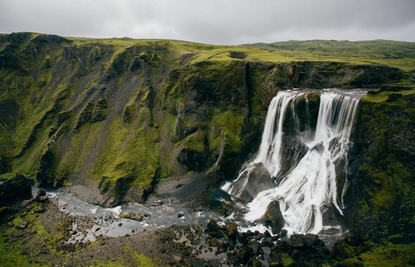 A photo of a green grassy cliff with a waterfall in Iceland. 