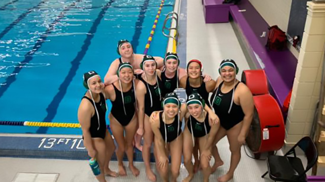 The women's water polo team poses by the edge of the pool