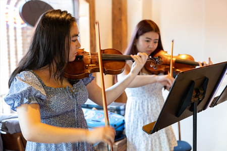 Two students in dresses playing violins