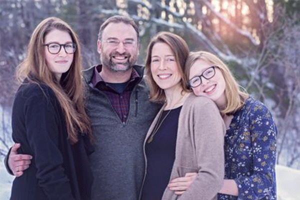 The Parrott's and their two daughters posing outdoors in the winter. 