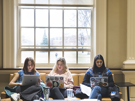 A photo of three women seated, studying in Baker Library on their computers.