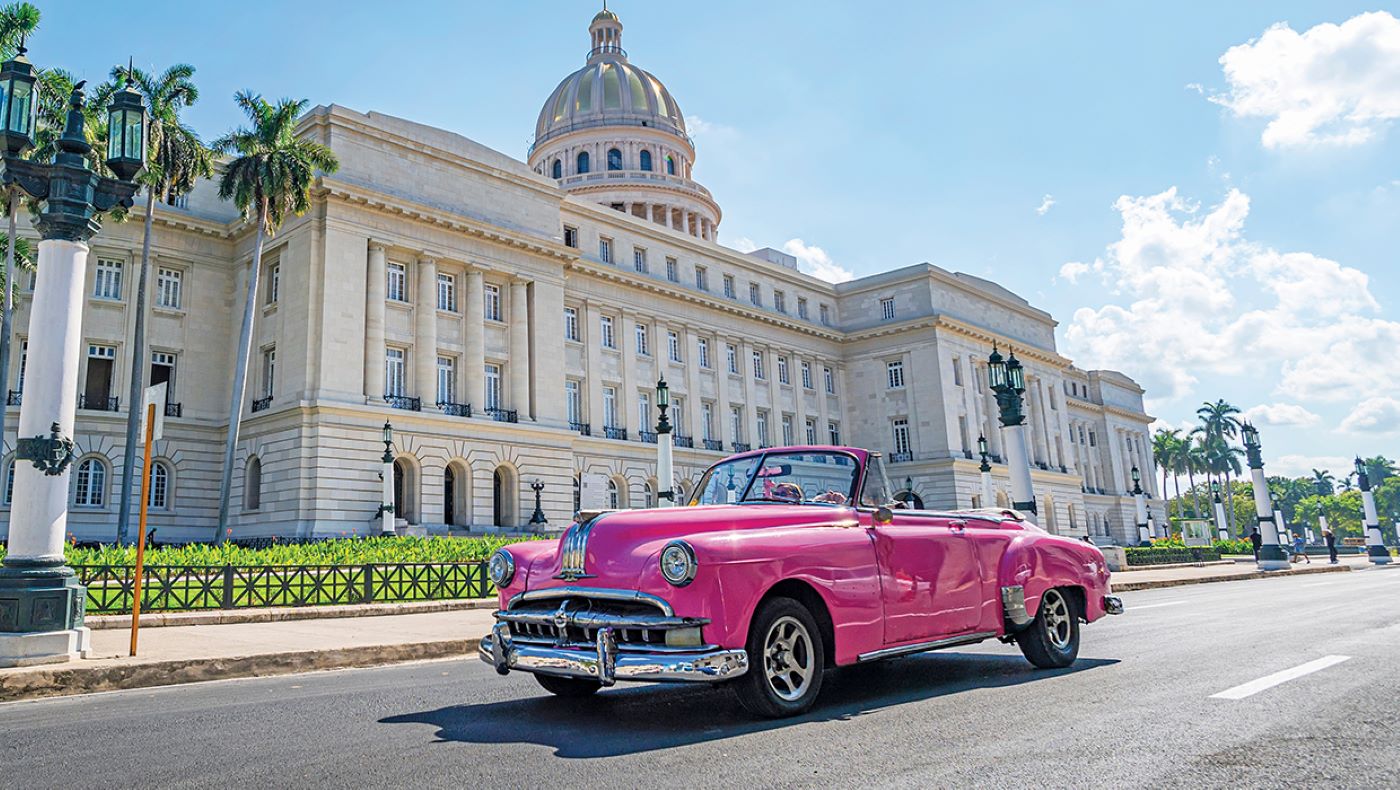 bright pink convertible in front of building in havana