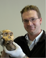 Jeremy DeSilva in gloves holding an ancient skull