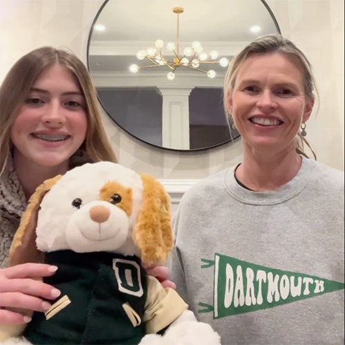 A Dartmouth alumna and her daughter welcome the Class of 2028. The daughter is holding a teddy bear with a Dartmouth jacket on.