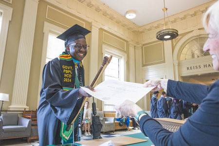 A student receiving his paper diploma in the lobby of Baker. 