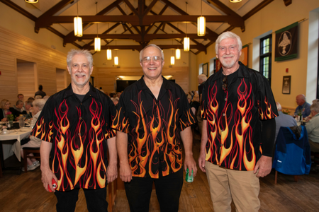 Three people in matching black shirts with flames on them. 
