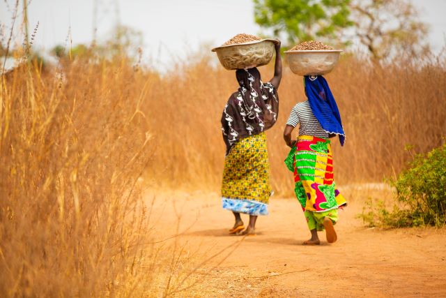 Two Ghanaian women holding baskets full of food on their heads