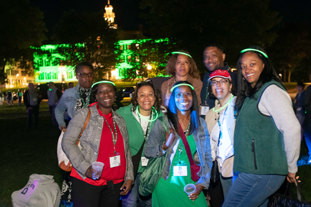 Group of alums with glow sticks smiling at On the Green