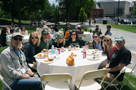 Alums gathered at a table smiling at the Community Lunch