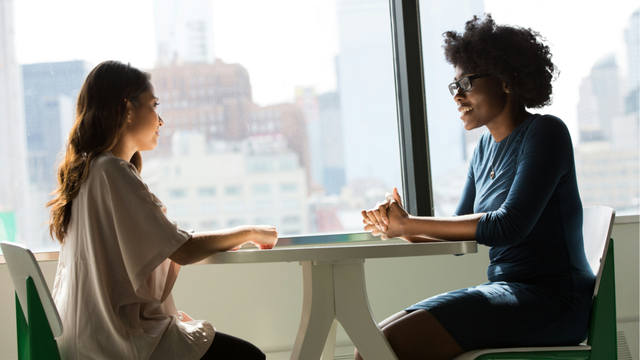 Two people seated at a table having a conversation