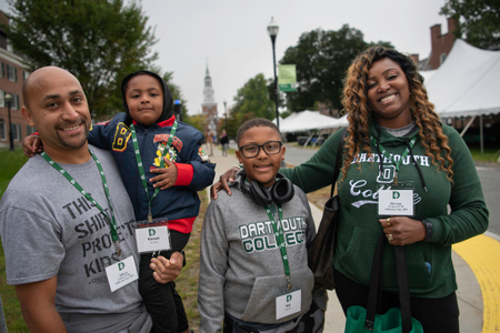 A family with two children on campus. Two of them are wearing Dartmouth gear. 