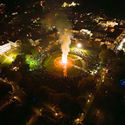 An aerial shot of the Homecoming bonfire lit up on the Green with spectators gathered around. 