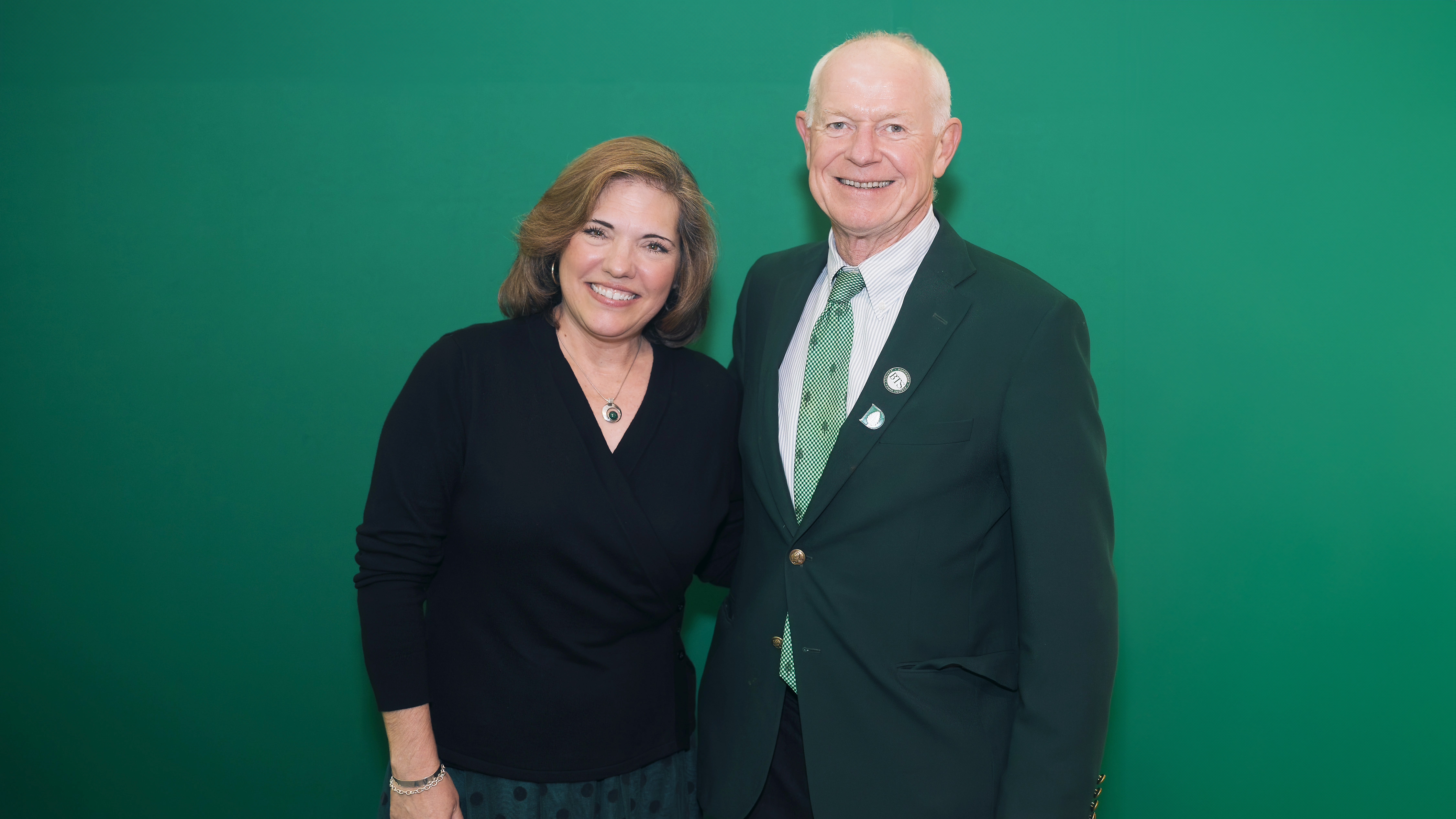 A photo of David Dietze, on the right, posing for a photo in front of a green background with the word Dartmouth on it. 