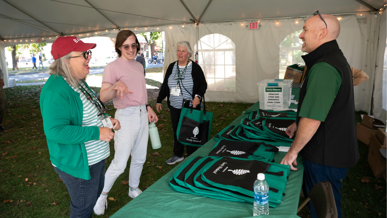 Three people talking to the Dartmouth staff person behind a registration table. 