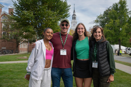 Two students and two parents posting with Baker Tower in the background. 