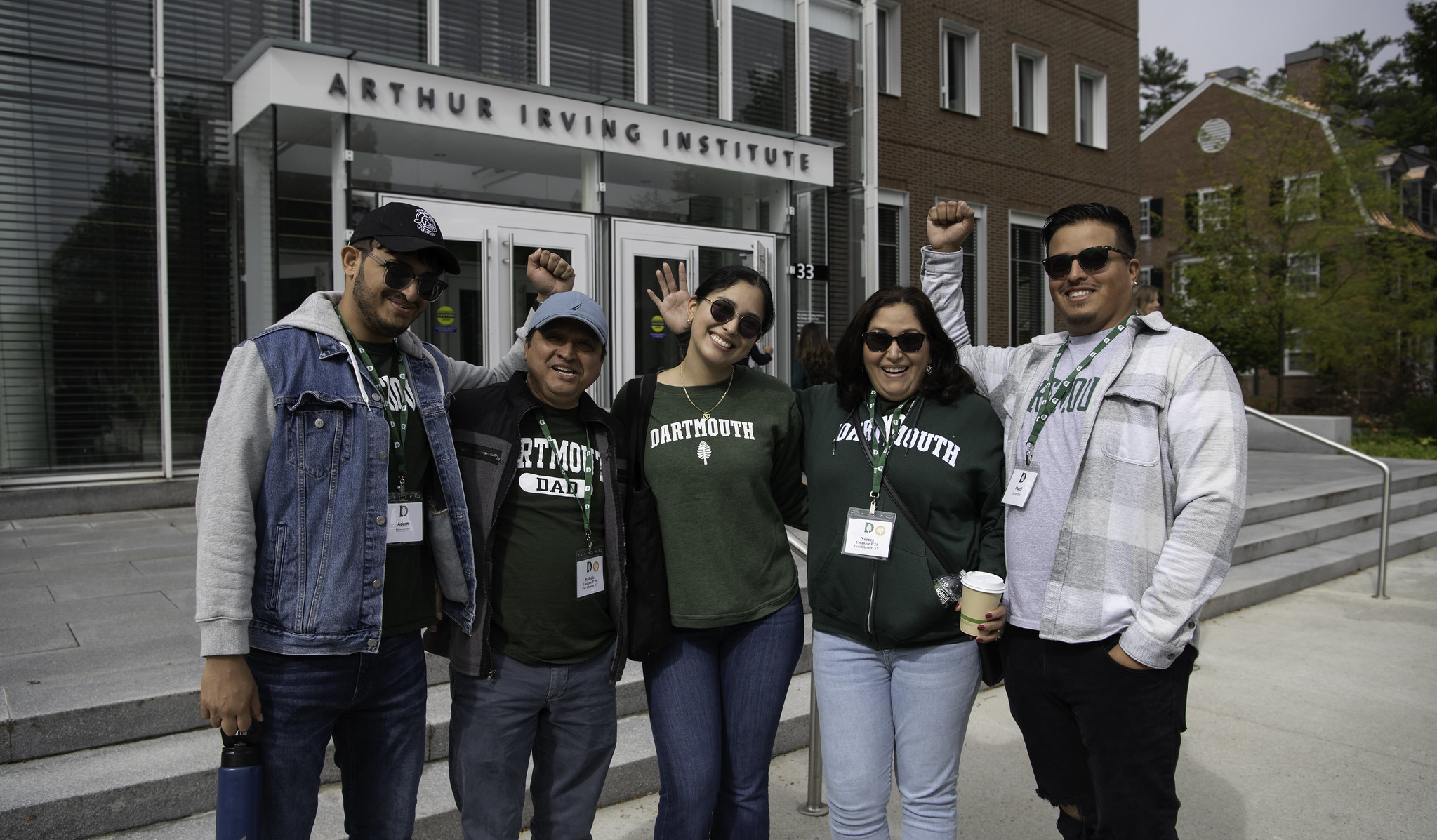 A family wearing Dartmouth gear posing in front of the Irving Institute building