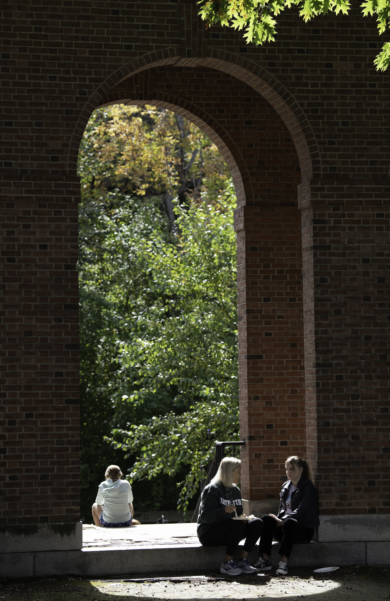 People sitting beneath an arch on campus. 