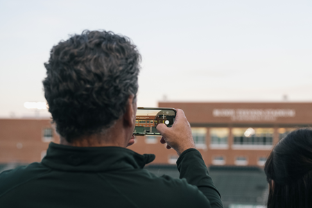 Buddy Teevens Stadium sign framed through a man's phone camera