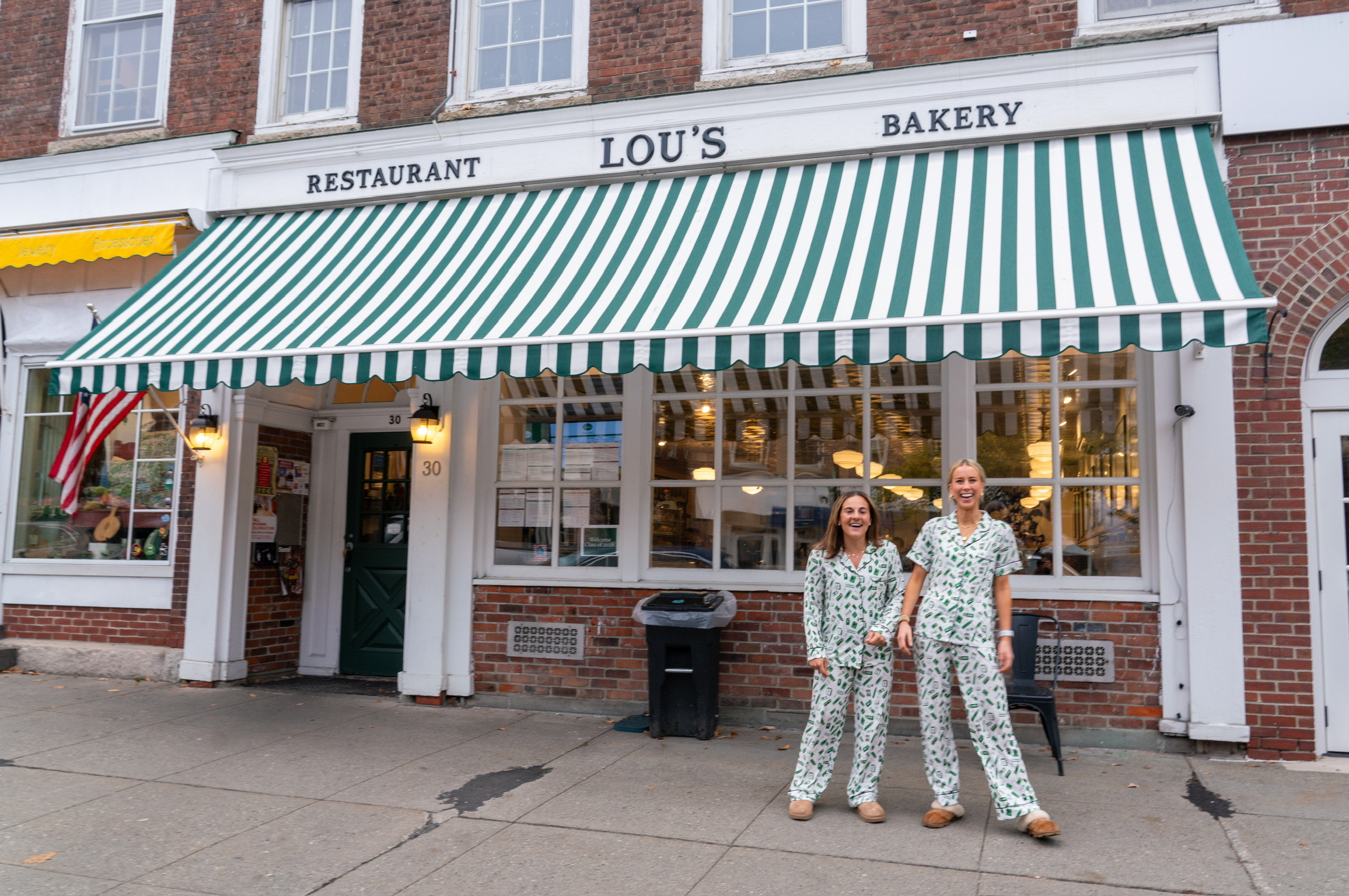 Two students wearing Sleepy Saturday pajamas standing in front of Lou's. 