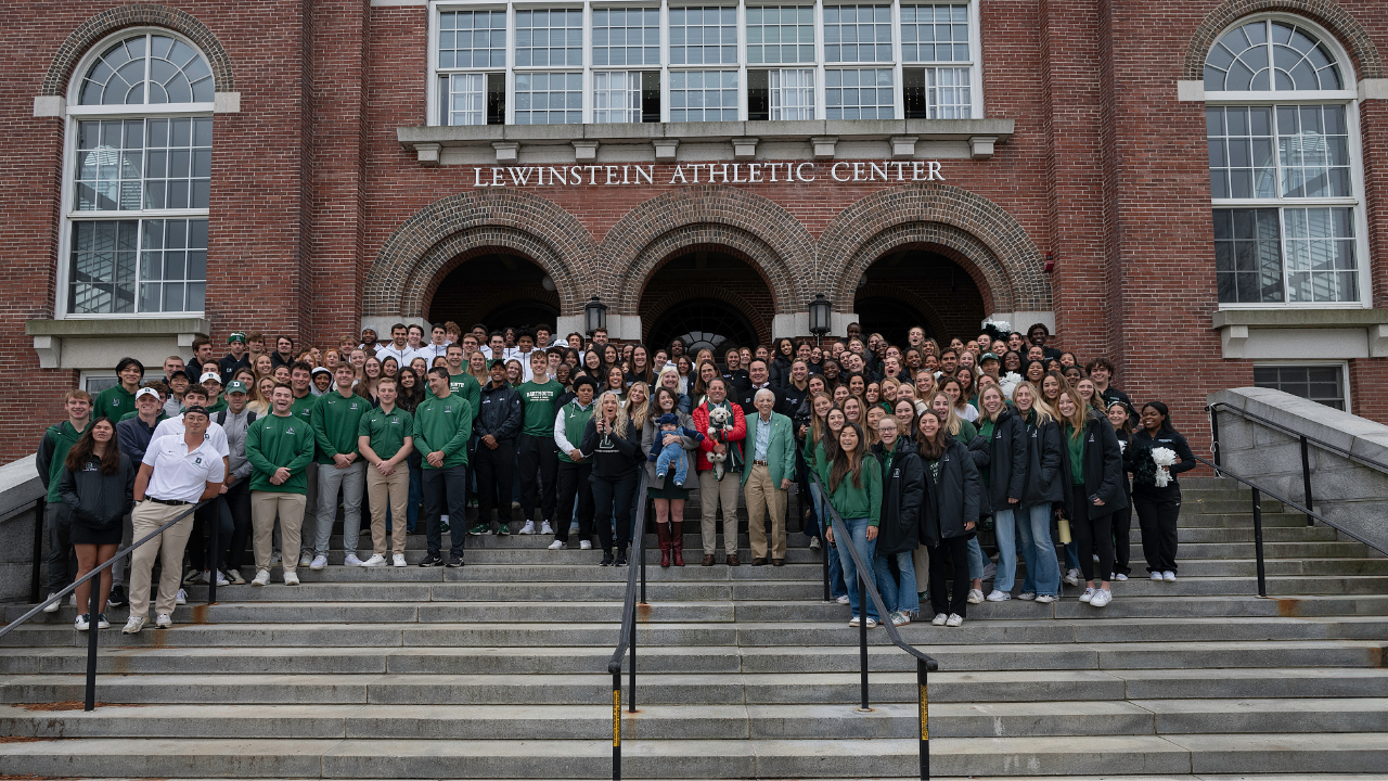 A group photo of people posing on the stairs of the Lewinstein Athletics Center