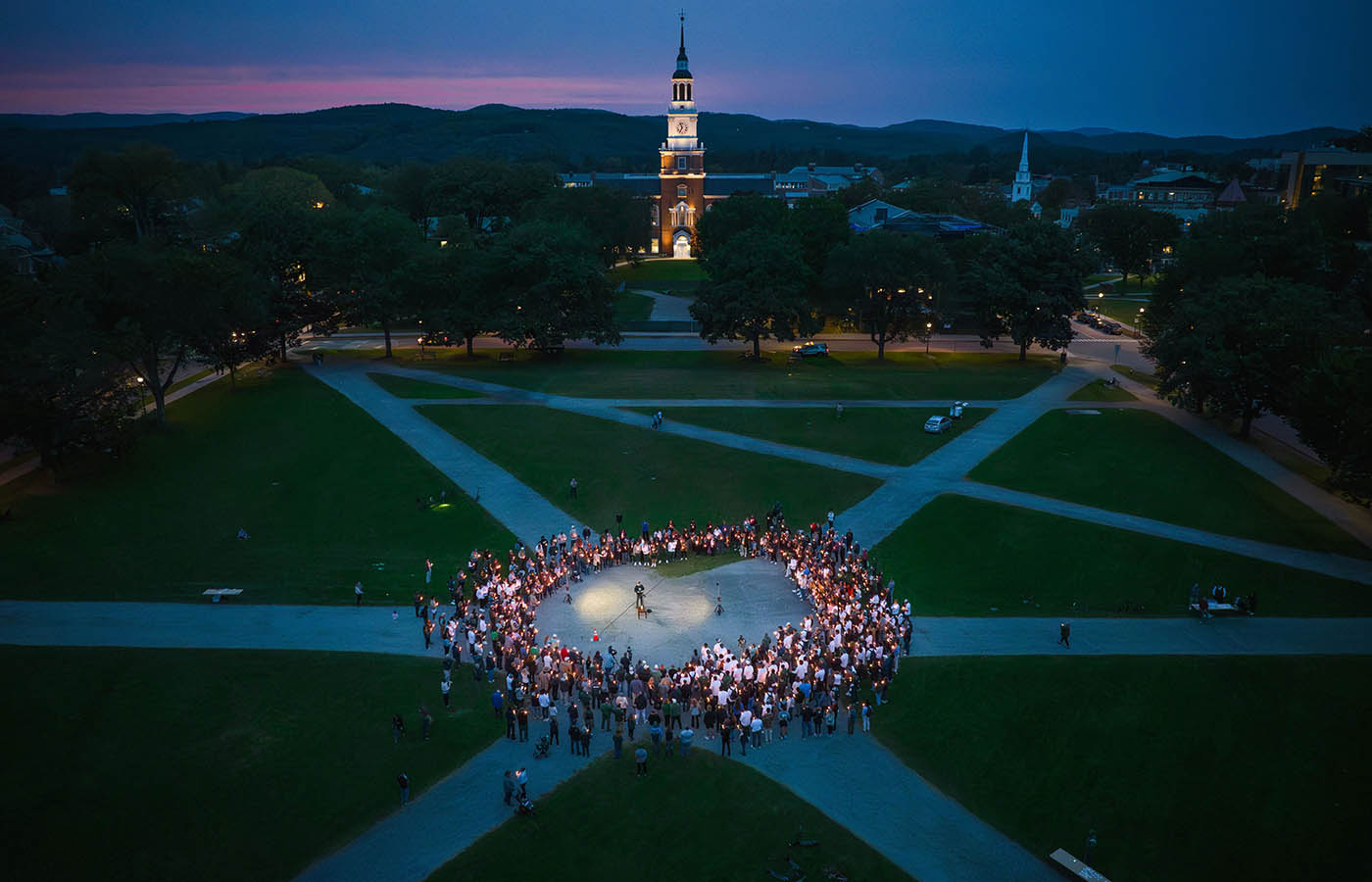 An aerial shot of a group gathered in a circle on the green in a candlelight vigil honoring the late Buddy Teevens. 