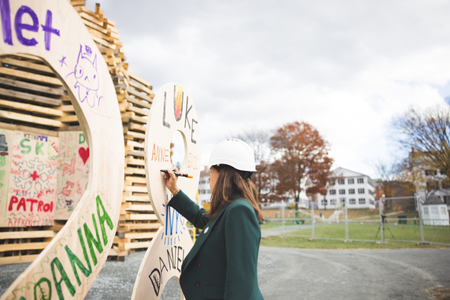 President Beilock writing on the wooden 28 bonfire topper. 