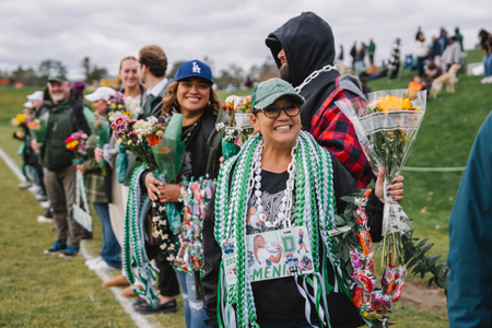 Parents and families with flowers and lots of beads and swag at the women's rugby game. 