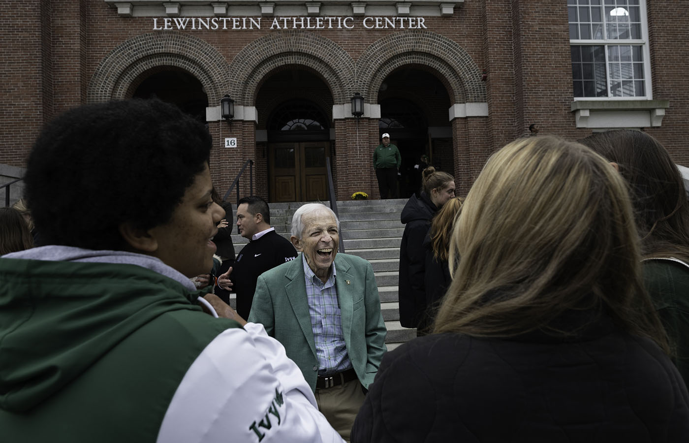 A photo of Stephen Lewinstein, joyfully smiling and laughing in front of the newly renamed Lewinstein Athletic Center