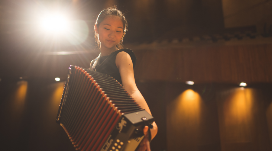 Abi Pak '26 playing the accordion on stage