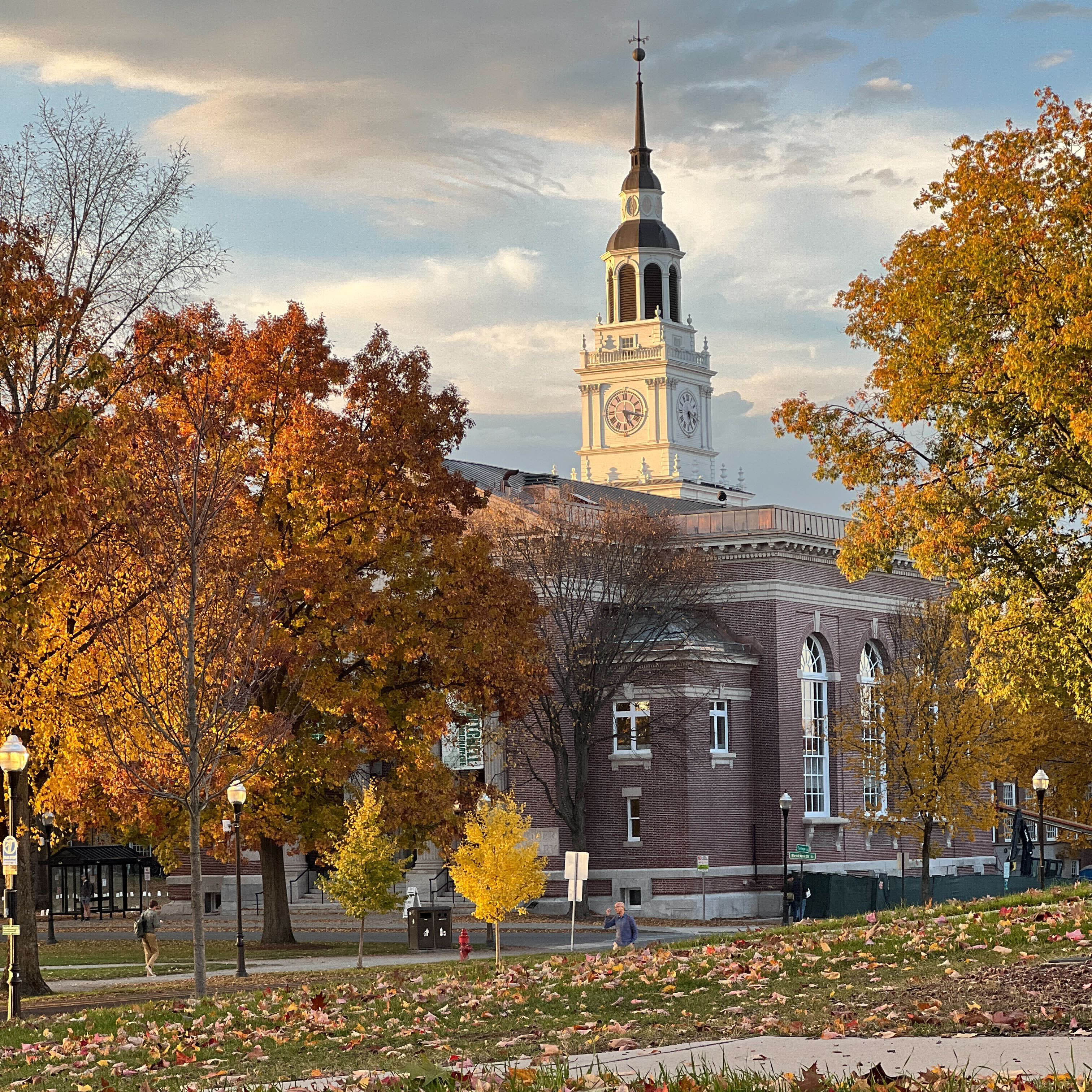 A golden hour shot of the exterior of Baker Tower surrounded by trees in peak fall foliage