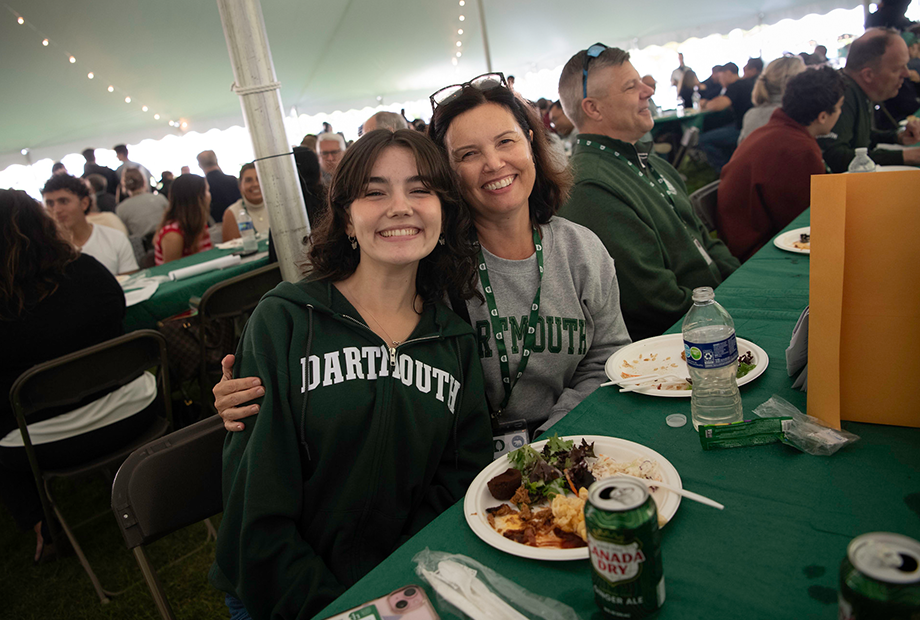 Mom and daughter smiling at table under Family Weekend dining tent