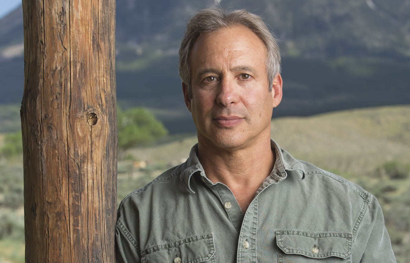 A portrait of Peter Heller standing with a mountain in the background