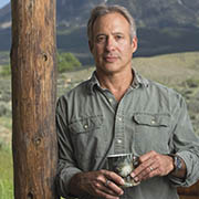 A portrait of Peter Heller standing with a mountain in the background