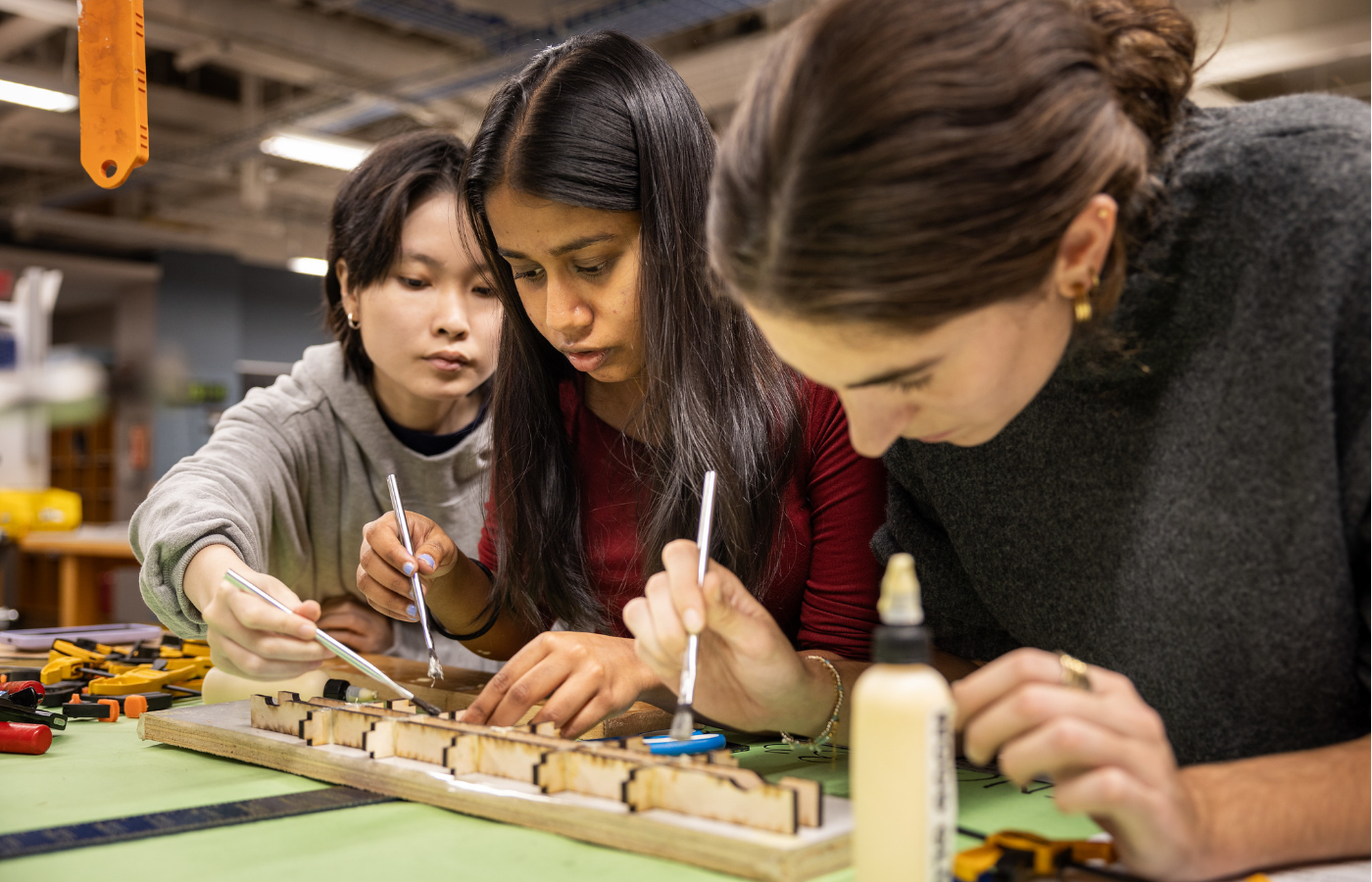 Three students working on a model sitting on a table top.