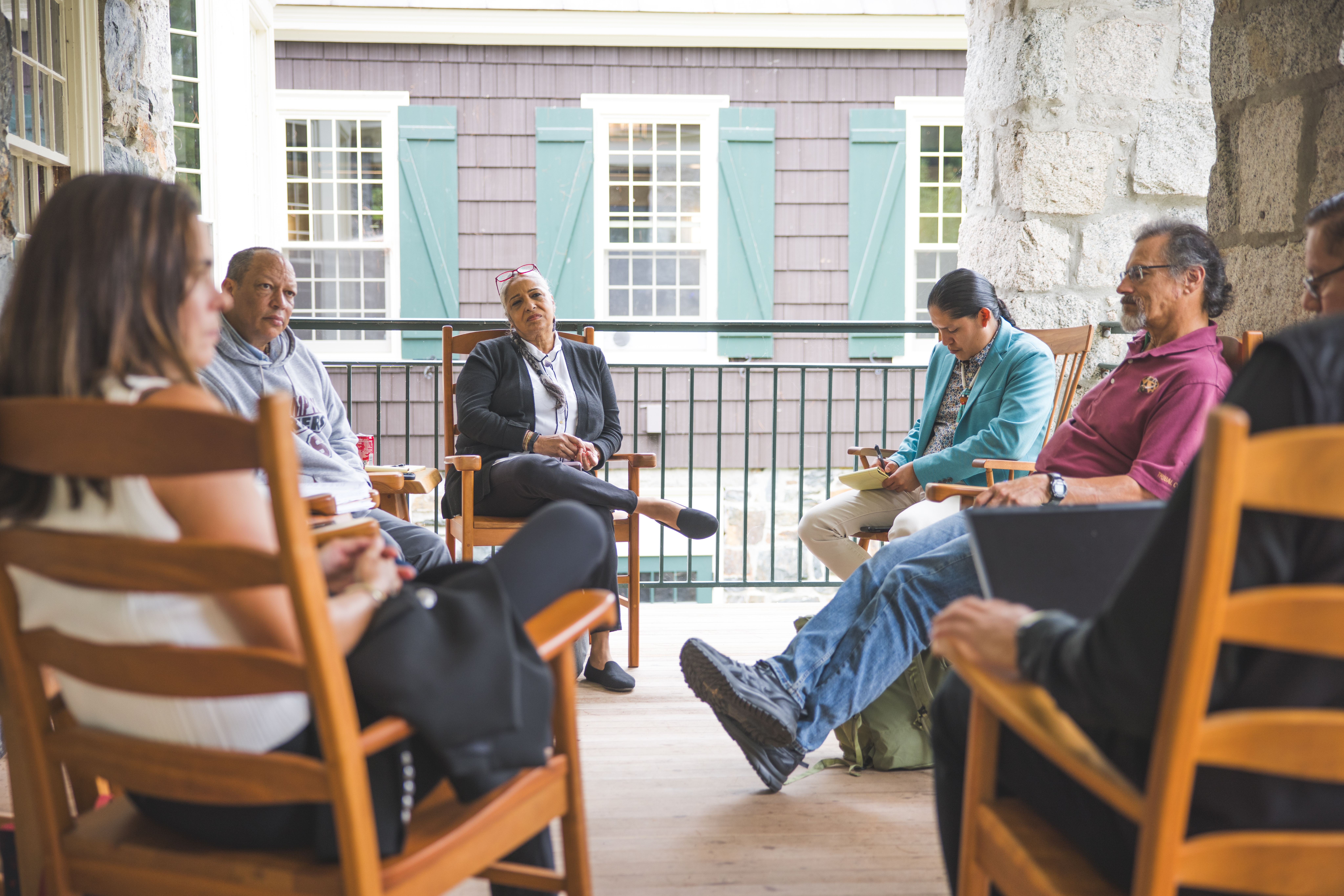A group of people sitting in a circle having a discussion on the balcony of the DOC house.