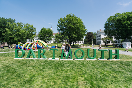 Alums posing for a photo in front of large letters spelling out Dartmouth
