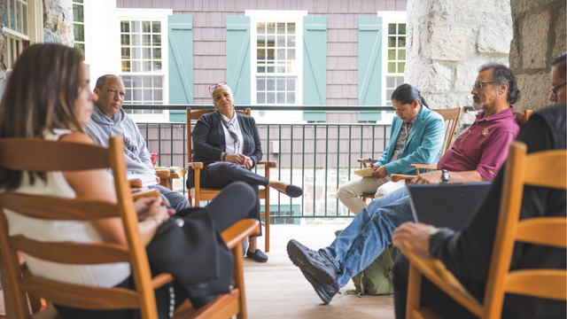 A group of people sitting in a circle having a discussion on the balcony of the DOC house.