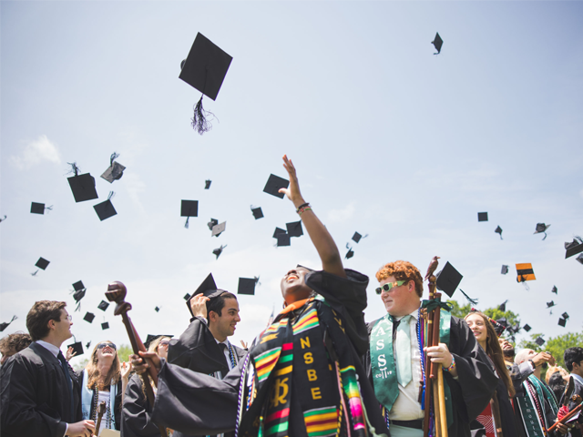 Class of 2025 grad throwing their cap in the air in celebration