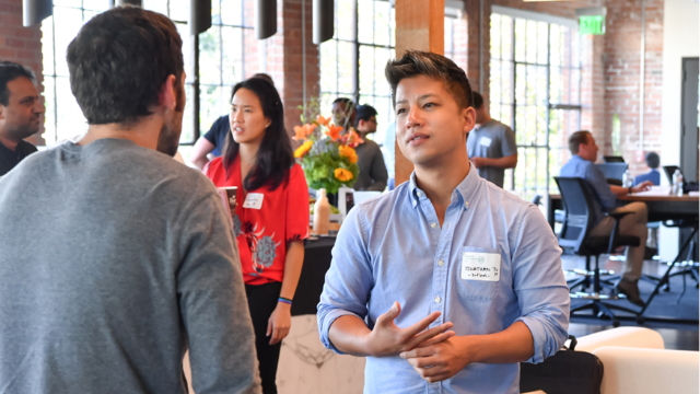 Two males facing each other having a conversation at a networking event.